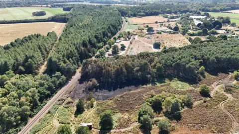 NNDC/NFRS An aerial drone shot shows a large area of woodland, some of which is blackened after a fire.