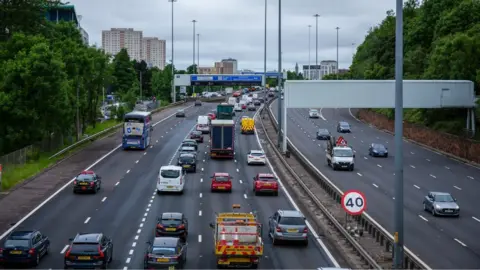 A general view of cars on a motorway, with high-rise buildings in the background 