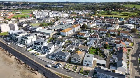 BBC A photo from a drone showing houses, a road, the edge of a beach and a sports field in Jersey