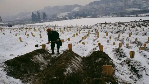 Sygma via Getty Images A gravedigger buries civilians killed in the siege of Sarajevo in 1993