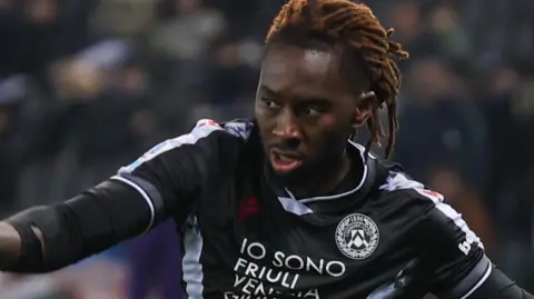 Udinese's Jordan Zemura in Serie A action, wearing black and white kit and black gloves