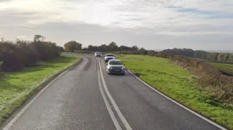 Google A single-lane carriageway with in the countryside. Image is taken from Google Street View.