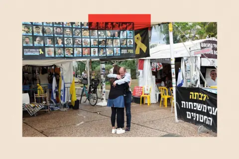 Reuters People hug next to banner with photos of hostages