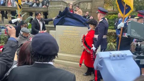 BBC People watching a war memorial being unveiled