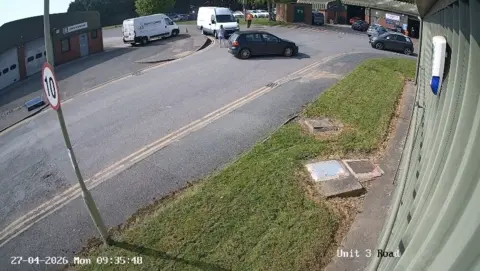 CCTV footage shows a white van driving towards a woman in the road stood next to a car