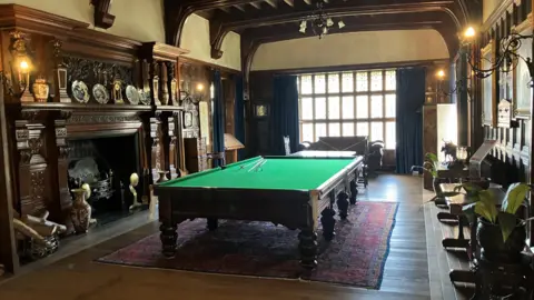 One of the rooms at Bramall Hall. There is a billiard table, antique furniture and oak panels on the walls. 