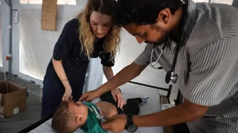 UK-Med A male and female doctor treating a young boy on an operating table 