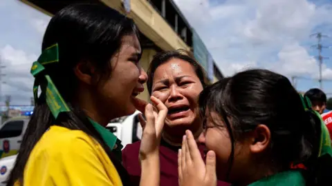Getty Images Two schoolgirls and a woman bursting into tears