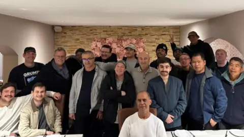 Crowley Nineteen men, of various ages, look jubilant as they pose for a photograph. One person, who is at the back and on the left-hand side, is making a 'V' for victory or peace sign.