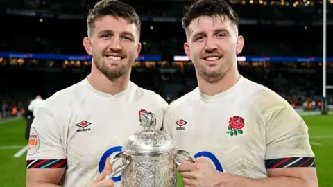 Ben Curry (left) and Tom Curry in England shirts holding a silver trophy