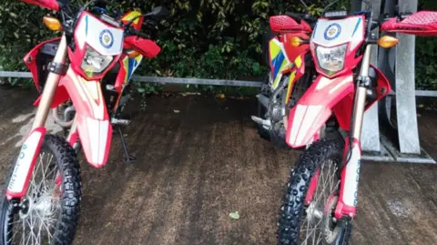 West Midlands Police Two red and white bikes are side by side. They both have the West Midlands Police logo on the front.