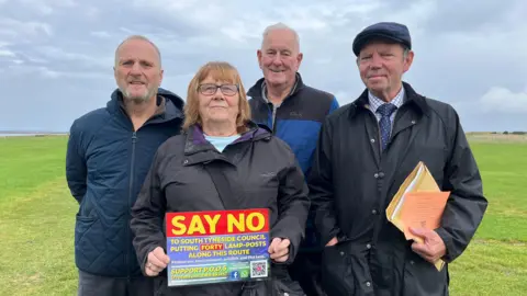 Campaigners stand on the Leas, holding up a sign which asks people to support their petition