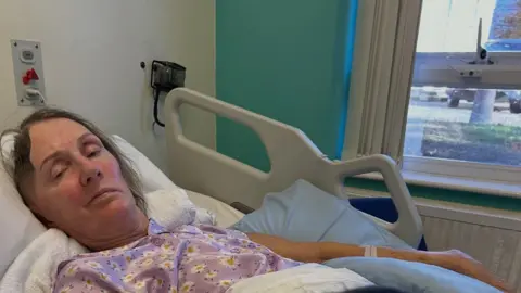 Warren Bullock A woman is in a purple nightgown in hospital bed