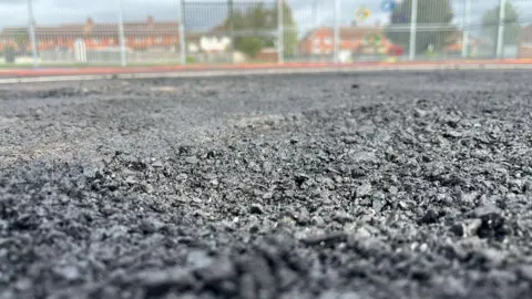 Bridgwater Town Council A close up of the damanged sports pitch showing the surface, which is dark grey, has broken up and is uneven