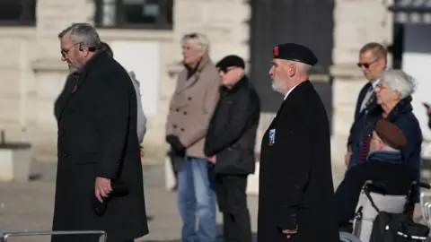 PA Media People stand by the First World War Soldier statue in Market Square in Dover for a two-minute silence to mark Armistice Day. 