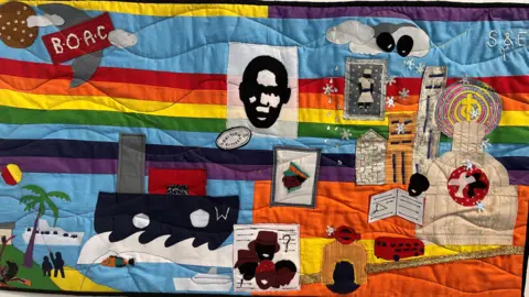 Jon Wright/BBC A quilt with a boat, bright colours, a London bus