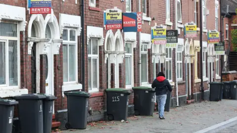 Getty Images A man walks past a street of terraced houses advertising properties for rent in Stoke-on-Trent