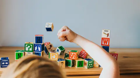 Getty Images A child smashes a tower of blocks with their fist. Only the back of the child's head and their fist is in view.