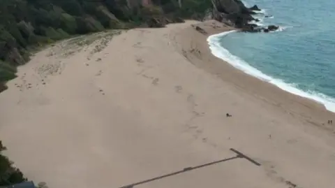 An aerial view of a white sandy beach surrounded by cliffs 