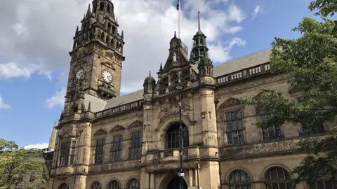 A Victorian town hall in a gothic style with brick, a clock tower, a balcony and large arched windows