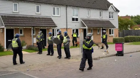 PA Media Police using shields and dogs as protection during an anti-immigration demonstration as they stand in front of houses near the Holiday Inn Express in Rotherham