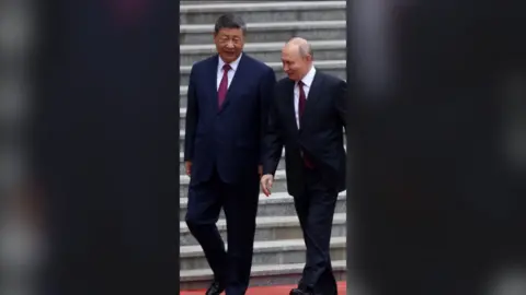 Chinese President Xi Jinping and Russian President Vladimir Putin in conversation at the bottom of some steps.