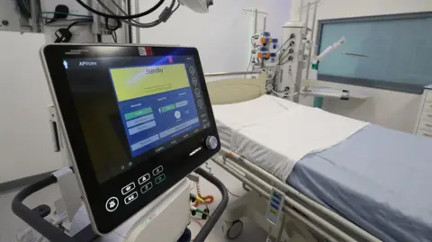 PA Media An empty intensive care bed with medical equipment surrounding it