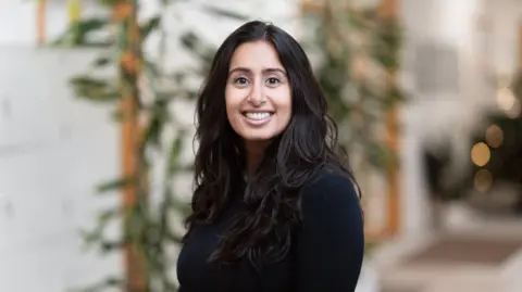 NatureMetrics A woman stands smiling in front of foliage