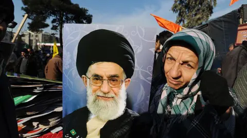 Getty Images An Iranian woman poses with a portrait of Supreme Leader Ayatollah Ali Khamenei 