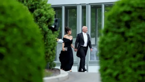 Reuters Jeff Bezos is seen walking outside the White House with his wife Lauren Sanchez. They are both in black tie attire. 