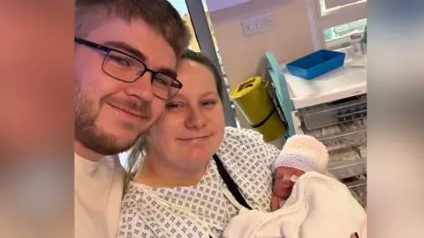 Family handout A mother and father holding their newborn baby at a hospital. 