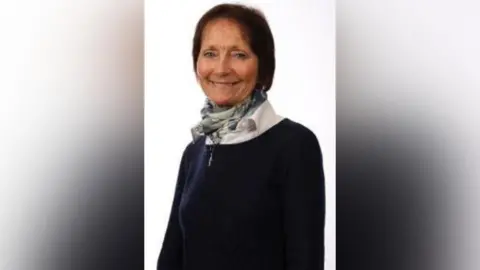 A woman with short dark hair smiles at the camera