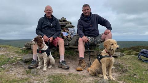 Barry Curtis and a friend at the top of a peak with two dogs