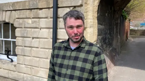 Photo of Daniel Gail standing in front of a white stone building