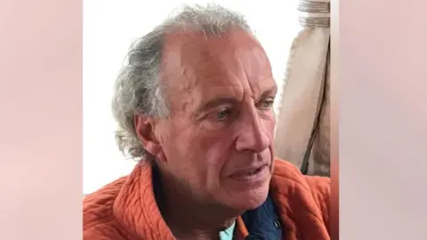 Police Scotland Head shot of Ian Catterson, sitting down and looking to the right, wearing an orange jacket 