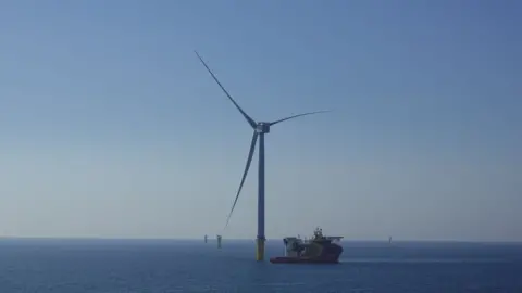 SSE Renewables One of the wind turbines in the sea with a ship moored alongside it