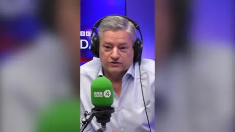 Ted Sarandos wears a white shirt and headphones