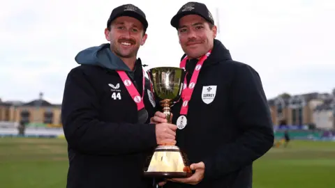 Surrey all-rounder Cameron Steel and captain Rory Burns holding the County Championship trophy