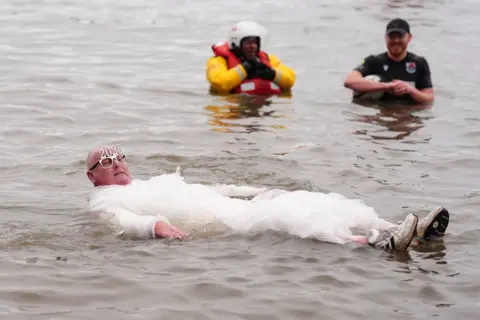 PA Media A man wrapped in bubble wrap floats in the water with 2025 glasses.