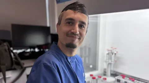 Man in a blue lab coat in a scientific laboratory