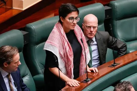 MP wears a red and white chequered Palestinian scarf in Parliament