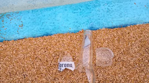 Ipswich Borough Council A broken bottle is on the floor next to the edge of the pool