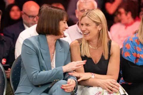 PA  Rachel Reeves (left) and her sister Ellie Reeves seen laughing together, sitting next to each other at a campaign rally 