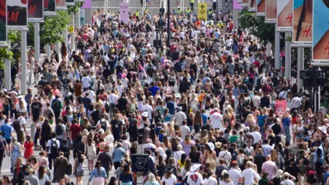 A large crowd of people walk outside Wembley Stadium.