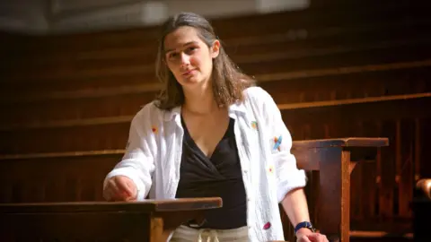 Dr Amanda Cole sitting at a lecture hall bench