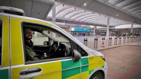 A man in an emergency services vehicle. He is smiling.