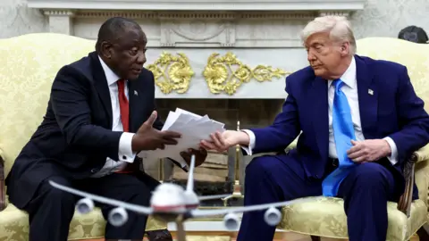 US President Donald Trump hands over to South African President Cyril Ramaphosa copies of articles that he said showed white South Africans who had been killed, in the Oval Office of the White House in Washington, DC, May 21
