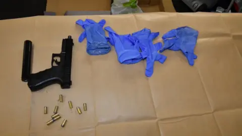 Nottinghamshire Police A black handgun and silencer with bullets and four gloves