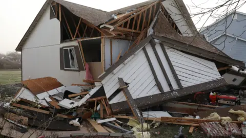 Debris piled around a downed home in Florissant, Missouri on 15 March