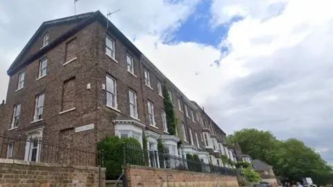 Terrace of tall Georgian properties beside a river all with large white framed windows